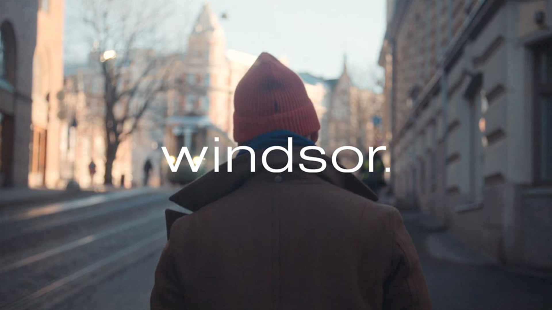 Man sieht einen Mann von hinten, der durch eine Stadt geht, über dem Bild ist in weißer Schrift das Wort "windsor" gelegt.